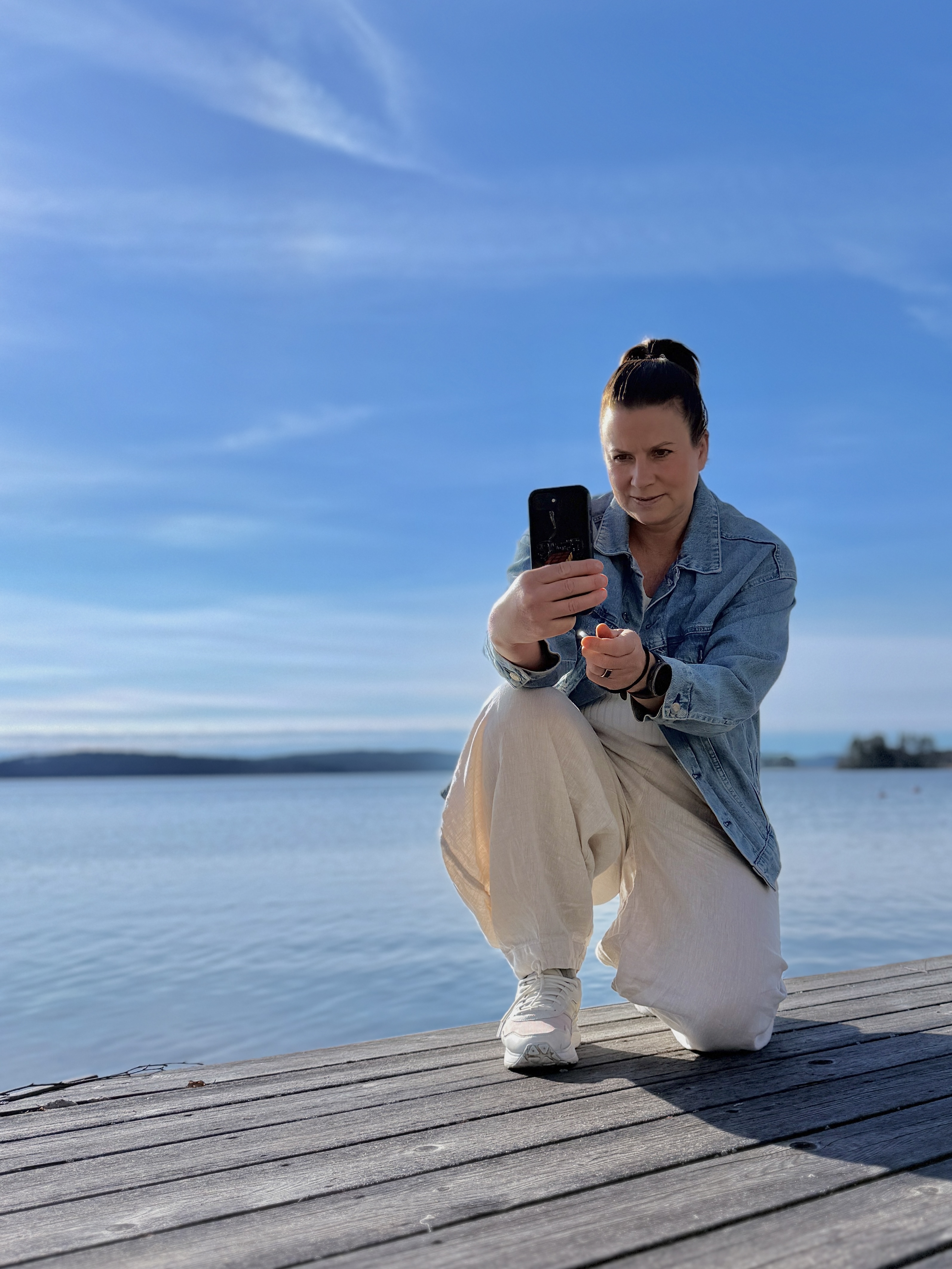 Mari Stenman kuvaamassa puhelimella laiturilla